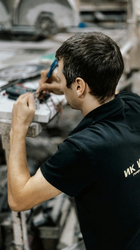 Focused technician repairing electronic circuits in a workshop setting.